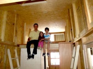 Crianças e pai na casa pequena em construção